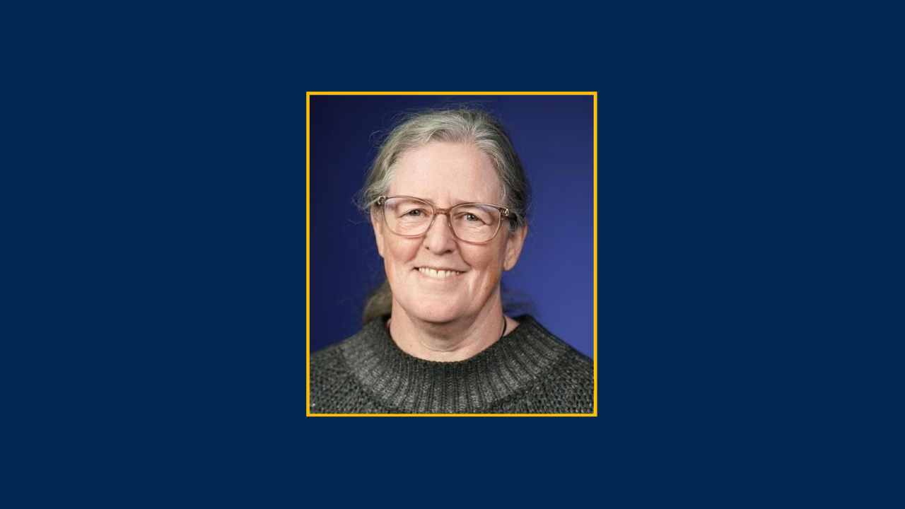 Smiling older woman with glasses and gray hair, portrait photograph on blue background