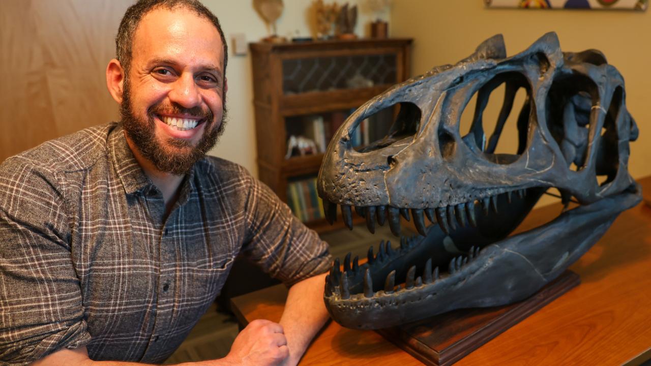 David Gold sits next to a dinosaur head