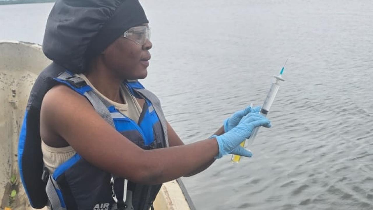 Sunjo Claris sits in a boat collecting water samples.