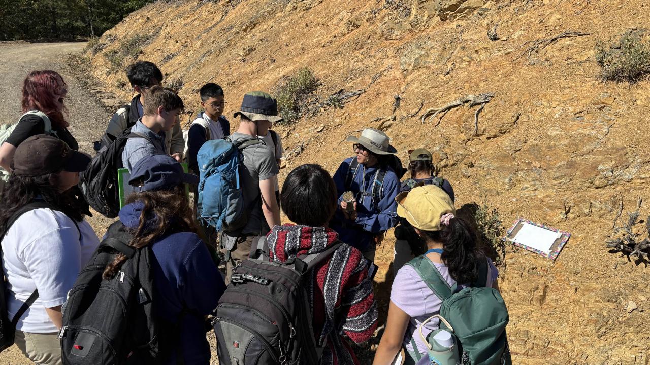 A group of people gathered outdoors near a rocky hillside