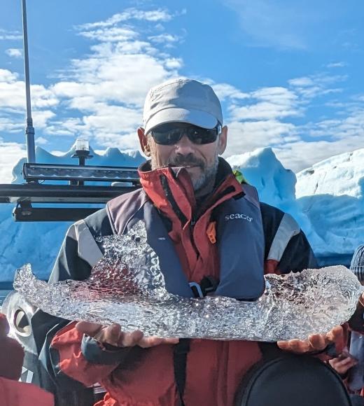Nicholas Pinter holding a large icicle and snow caps in the background