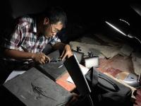 A male student sitting at a table measuring a plesiosaur fossil.