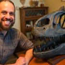 David Gold sits next to a dinosaur head