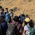 A group of people gathered outdoors near a rocky hillside